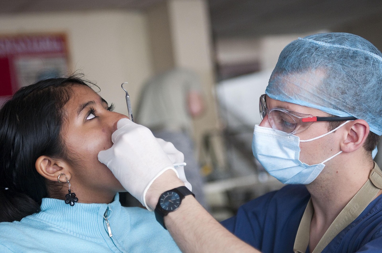 A dentist treating a patient while an assistant helps